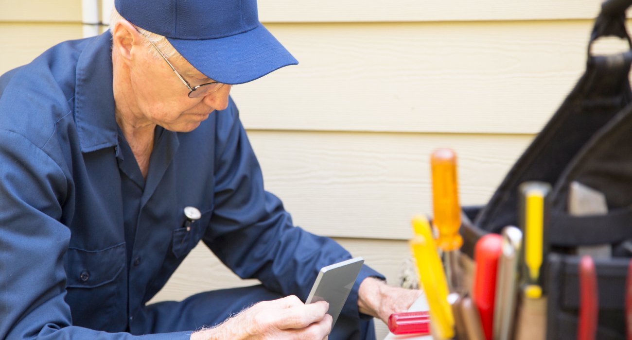 HVAC repair man with white hair fixing an HVAC unit