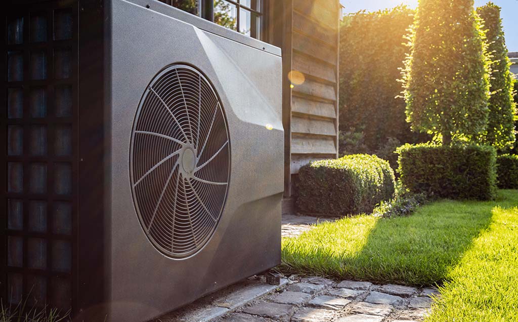 Outdoor HVAC unit installed next to a well-maintained garden, illustrating a modern setup for HVAC system replacement to enhance energy efficiency and home comfort.