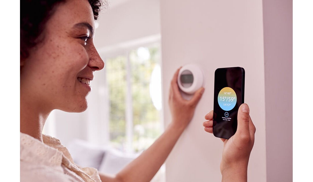 Close Up Of Woman Using App on Mobile Phone To Control Central Heating Thermostat